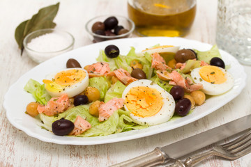 fish salad with olives on white dish with olive oil