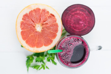 Grapefruit, beet, parsley and juice on white wooden table.