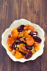 dry fruits and nuts in white dish on wooden background