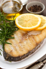grilled fish with lemon in white dish on wooden background