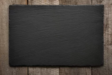 Fotobehang Black slate tile on wooden background. Top view. © svetlana_cherruty