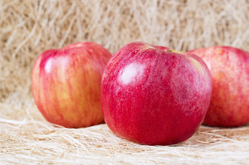 Fresh ripe apples on the straw rustic background.