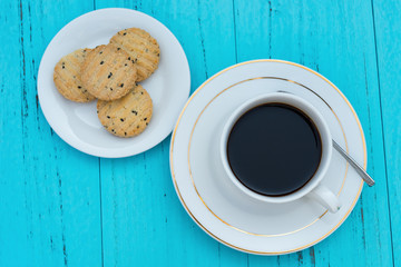 top view cup of coffee and biscuit with seasame on blue background