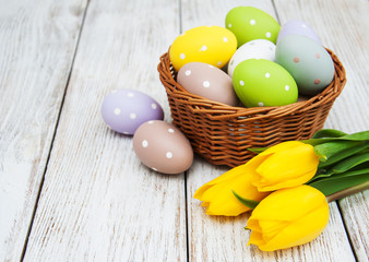 Obraz na płótnie Canvas Basket with easter eggs and tulips