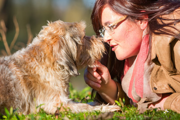 young woman lies with her dog in the grass