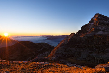 Obraz na płótnie Canvas Mountain range at sunset, backlight with sunburst, italian Alps