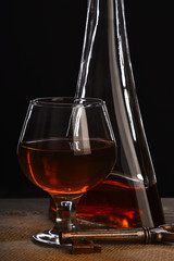 glass, carafe with cognac, whiskey and key on wooden table