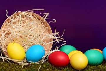 painted easter colorful eggs in wooden box on violet background