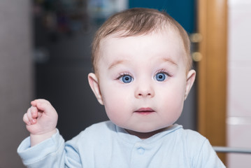 portrait of adorable baby girl / boy with big blue eyes. cute baby points his finger and looks into the camera
