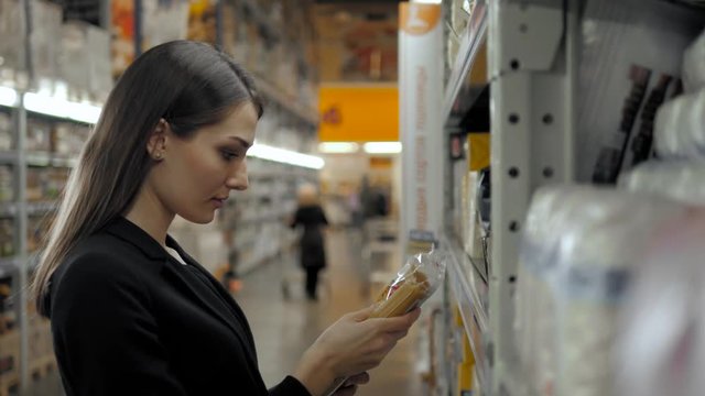 Woman choosing spaghetti italian pasta in grocery store. Brunette shopping in food supermarket