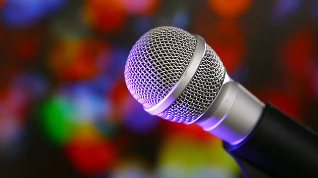 Microphone on stage with colorfull lighting and blurry background.