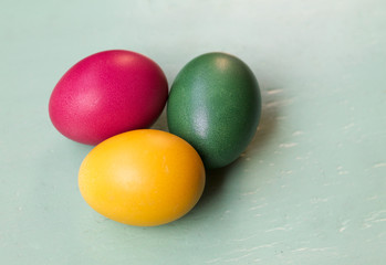 three colored easter eggs on old green wood