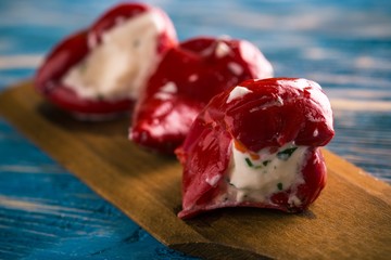 Three red pepper filled by cheese on wooden spoon