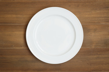 Top view of empty white dish on wooden background