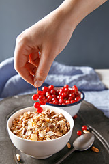 Cereals with currants on a wooden platter. Woman decorating oatmeal with berry fruit. Healthy breakfast.