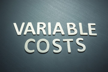 Variable costs written with wooden letters on a green background
