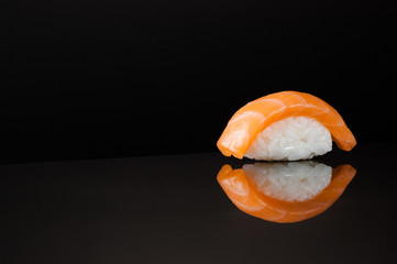 closeup of sushi with rice on black background with reflection