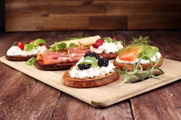 Bread Brushetta or authentic traditional spanish tapas set for lunch table. Sharing antipasti on party or summer picnic time over wooden rustic background.