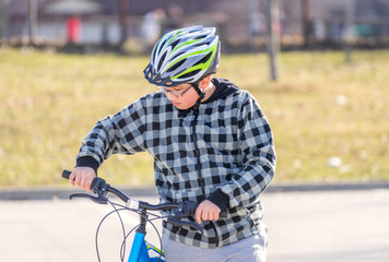 Obraz premium Preteen boy walking bicycle looking at handlebars, getting ready to ride