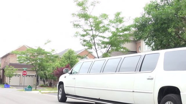 Wedding car decoration. Stretch limo. White limousine. White stretch limousine with partly cloudy blue sky. Long white limousine with spoked wheels. White limousine next to a residential house. Street