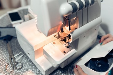 White modern overlock machine, woman hitting a piece of cloth on a small table.