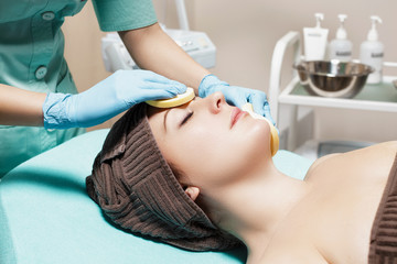 doctor beautician cleanses skin woman with sponge. cosmetology treatment skincare face. Spa procedures
