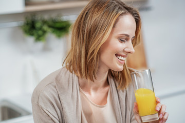 Joyful young woman drinking healthy beverage in kitchen