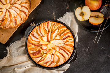 Apple pie in a portioned cast-iron frying pan, on a black stone table. With apples Top view, copy space