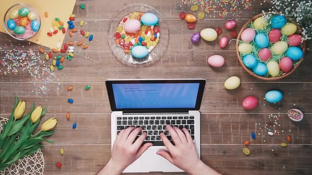 Man using laptop computer on table decorated with easter eggs Top view