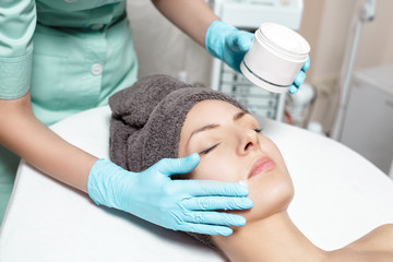 Obraz na płótnie Canvas beautician applies face cream on beautiful young woman in Spa salon. cosmetic procedure skin care. 