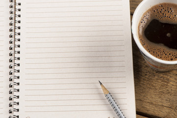 Black coffee with note paper and pencil on wood table.