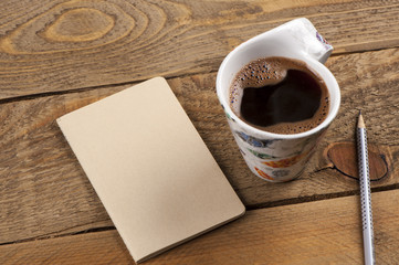 Black coffee with note paper and pencil on wood table.