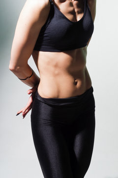 Slim woman belly against a light background.