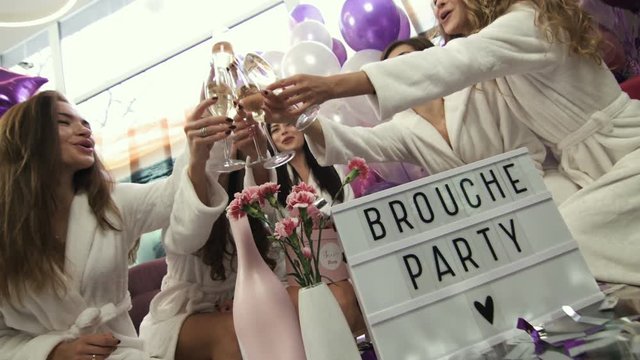 Beautiful girls in white robes drinking champagne at the opening party. Women celebrating at the beauty salon