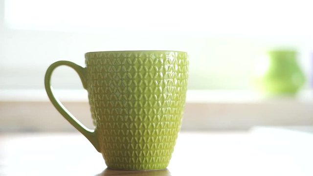 zielony kubek na tle okna