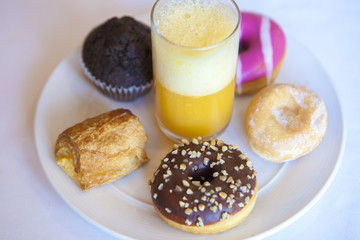 Plate full of pastries with orange juice glass
