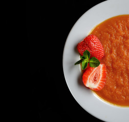 Pumpkin porridge, strawberry and mint on a black background