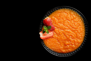 Pumpkin porridge, strawberry and mint on a black background