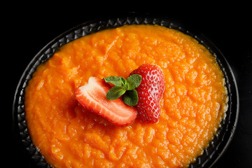 Pumpkin porridge, strawberry and mint on a black background