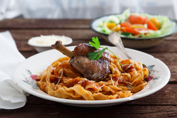 Braised Rabbit Leg in Tomato Sauce with Homemade pasta, dark rustic background