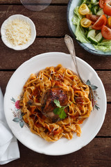Italian homemade pasta, pappardelle with tomato sauce and braised rabbit, top view close-up