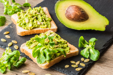 Healthy green food. Vegan sandwiches with avocado and vegetables on wooden background.