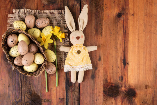 Easter background with vintage easter bunny decoration over old wood. Copy space, top view