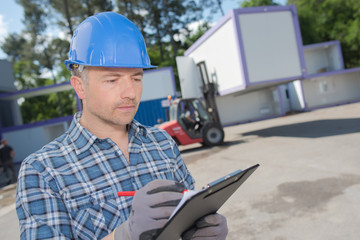 Man with clipboard, wearing protective helmet