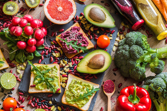 Healthy vegan food. Sandwiches and fresh vegetables on wooden background. Detox diet. Different colorful fresh juices. top view