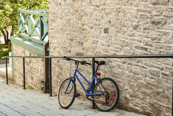Fototapeta na wymiar blue bicycle leaning against brick wall with a green railing on a hill