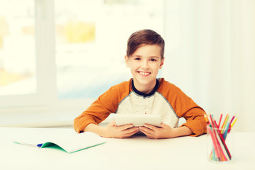 smiling boy with tablet pc and notebook at home