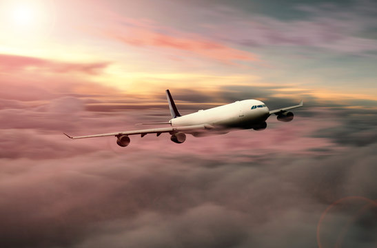 passenger plane flying at high altitude above clouds in evening sunlight