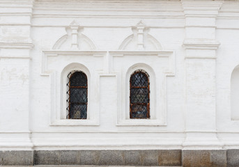 Fototapeta na wymiar White medieval church wall with latticed windows in arches shape.