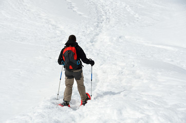 Fototapeta na wymiar Hiker with snowshoes in winter mountains, Alps, Italy